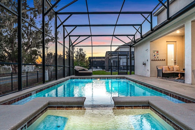 pool at dusk with a lanai and a patio area