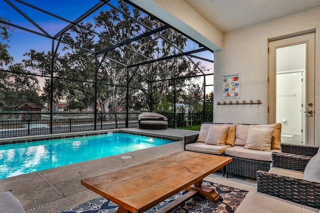 pool at dusk with a lanai, outdoor lounge area, and a patio