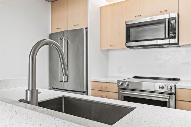 kitchen with light brown cabinets, stainless steel appliances, and light stone counters