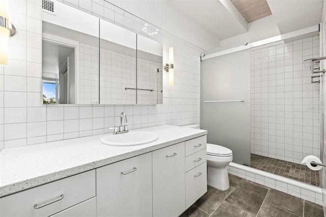 bathroom with tasteful backsplash, a tile shower, vanity, tile walls, and toilet