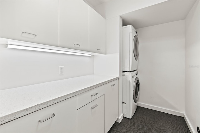 clothes washing area with cabinets and stacked washer and clothes dryer