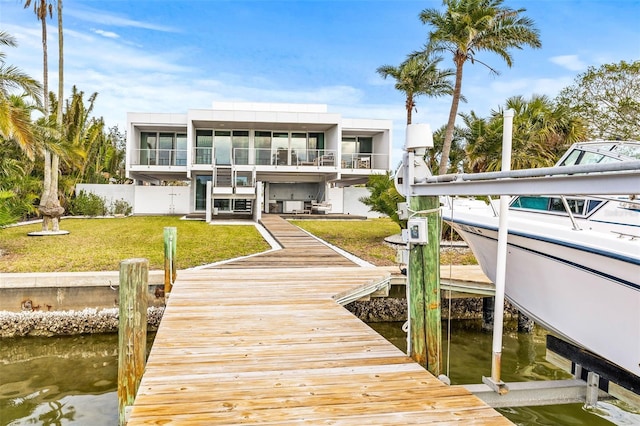 dock area with a lawn, a water view, and a balcony