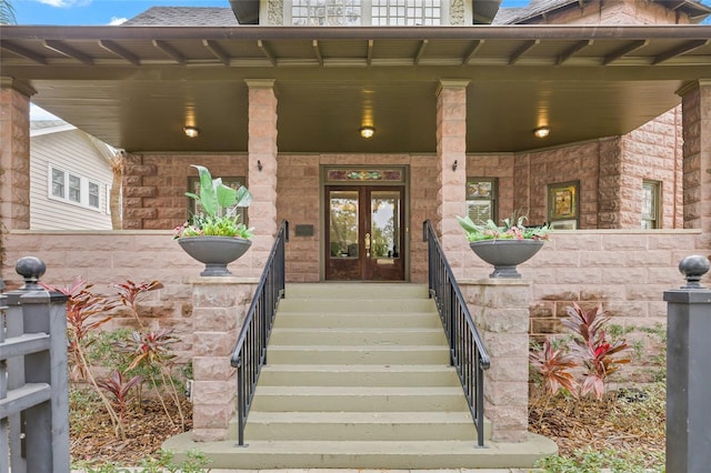 view of exterior entry featuring covered porch and french doors