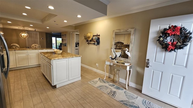 kitchen featuring crown molding, hanging light fixtures, a kitchen island, light stone countertops, and white cabinets