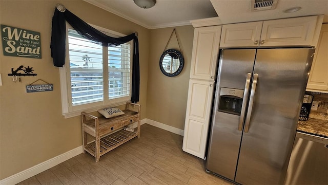 kitchen with appliances with stainless steel finishes, tasteful backsplash, white cabinetry, ornamental molding, and light hardwood / wood-style floors