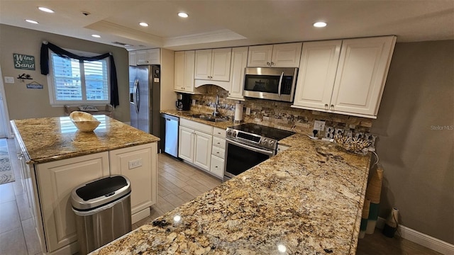 kitchen featuring white cabinetry, appliances with stainless steel finishes, a raised ceiling, and light stone counters