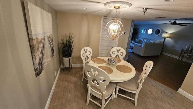 dining room with dark hardwood / wood-style flooring, ceiling fan with notable chandelier, and a textured ceiling