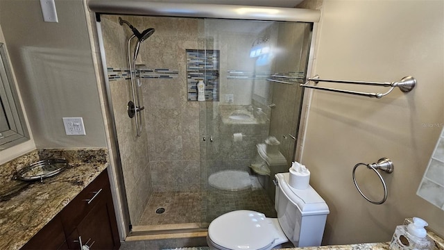 bathroom with a shower with door, vanity, and toilet