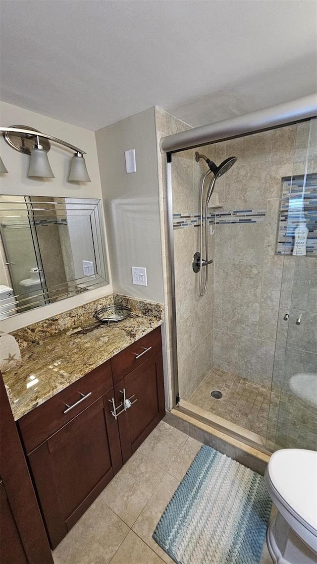 bathroom featuring an enclosed shower, vanity, tile patterned floors, and toilet