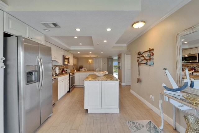 18325 Gulf Blvd Unit 407, Redington Shores, FL 33708 - kitchen with appliances with stainless steel finishes, ornamental molding, white cabinetry, a raised ceiling, and decorative backsplash