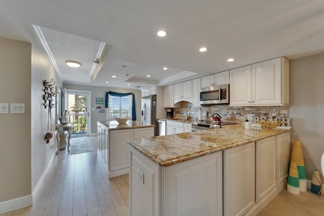 18325 Gulf Blvd Unit 407, Redington Shores, FL 33708 - kitchen with stainless steel appliances, baseboards, a center island, decorative backsplash, and light wood-style floors