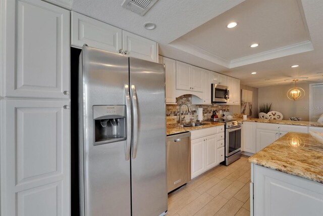 18325 Gulf Blvd Unit 407, Redington Shores, FL 33708 - kitchen with stainless steel appliances, a raised ceiling, a sink, white cabinetry, and tasteful backsplash