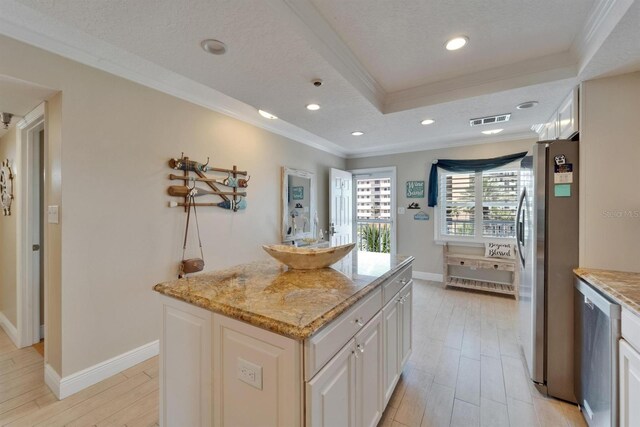 18325 Gulf Blvd Unit 407, Redington Shores, FL 33708 - kitchen with appliances with stainless steel finishes, ornamental molding, a raised ceiling, a kitchen island, and light stone counters