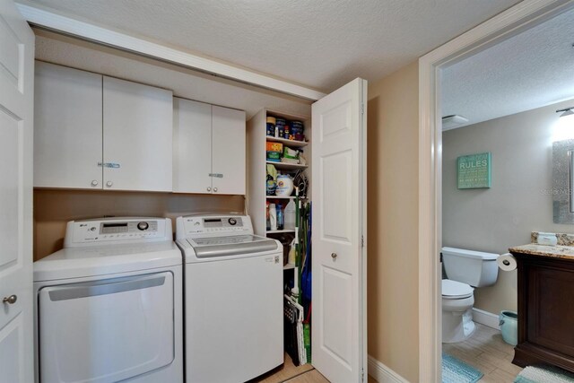 18325 Gulf Blvd Unit 407, Redington Shores, FL 33708 - laundry room with washer and clothes dryer, a textured ceiling, cabinet space, and baseboards
