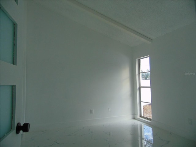 unfurnished room with beamed ceiling