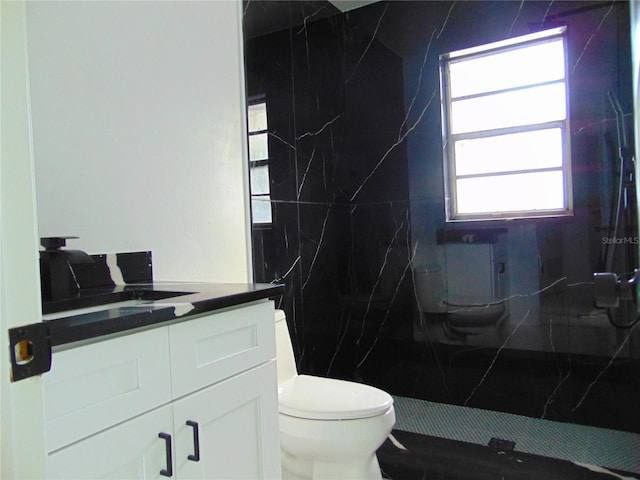 bathroom featuring vanity, toilet, and tiled shower