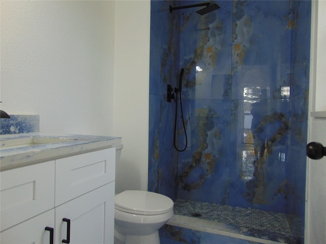 bathroom with vanity, toilet, and tiled shower