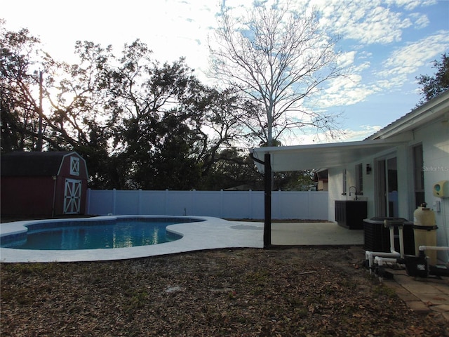 view of pool featuring a shed, cooling unit, and a patio area