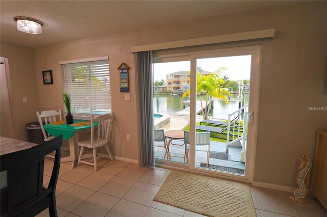 doorway featuring a water view and light tile patterned floors