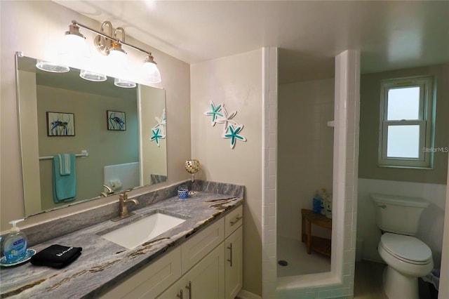 bathroom featuring a tile shower, vanity, and toilet