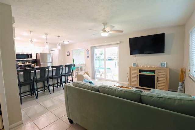 tiled living room featuring a fireplace and ceiling fan