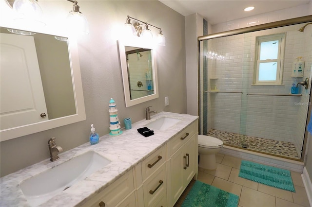 bathroom featuring tile patterned floors, vanity, toilet, and a shower with shower door