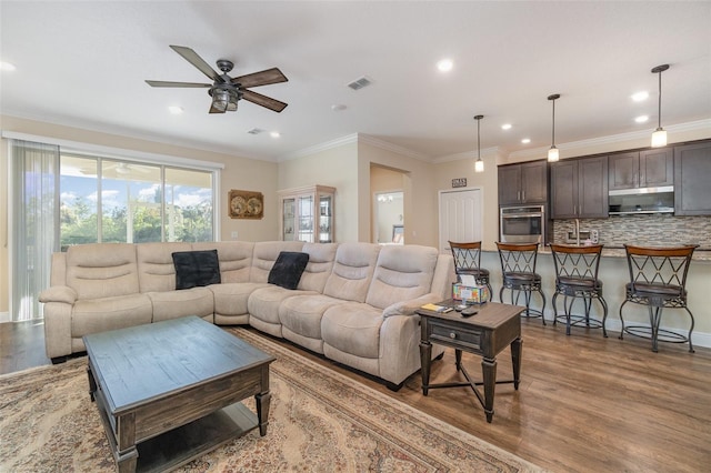 living room featuring hardwood / wood-style flooring, ceiling fan, and crown molding