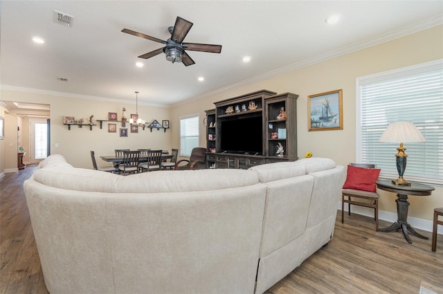 living room featuring crown molding, dark hardwood / wood-style flooring, and ceiling fan with notable chandelier