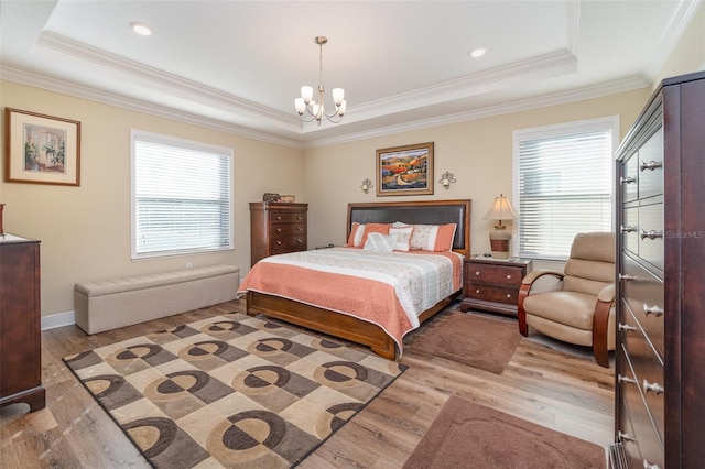 bedroom with a chandelier, light hardwood / wood-style flooring, a raised ceiling, and crown molding