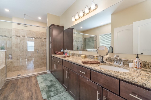 bathroom with hardwood / wood-style flooring, vanity, and a shower with shower door