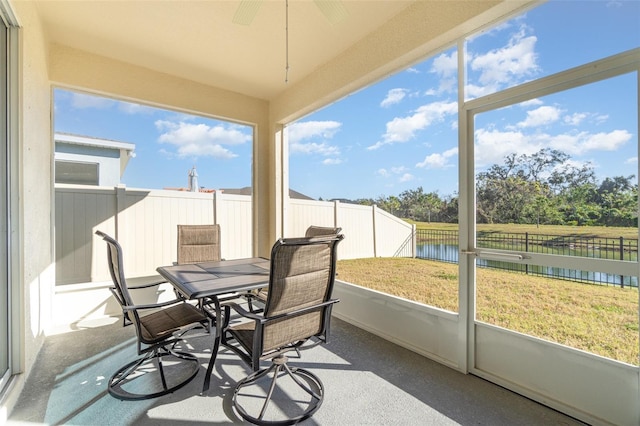 sunroom featuring a water view and ceiling fan