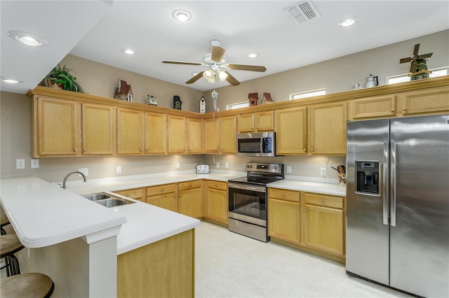 kitchen with appliances with stainless steel finishes, sink, kitchen peninsula, ceiling fan, and a breakfast bar area