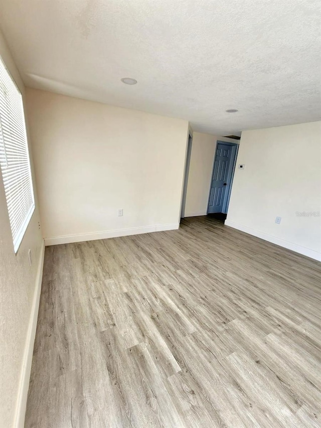 spare room with a textured ceiling and light wood-type flooring