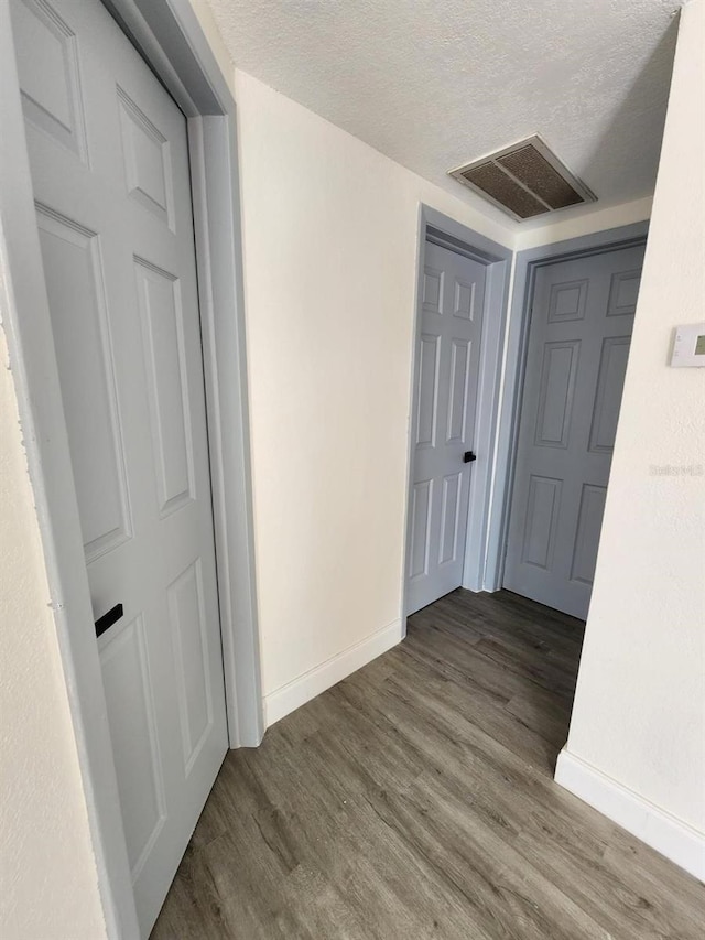 hall with a textured ceiling and hardwood / wood-style flooring