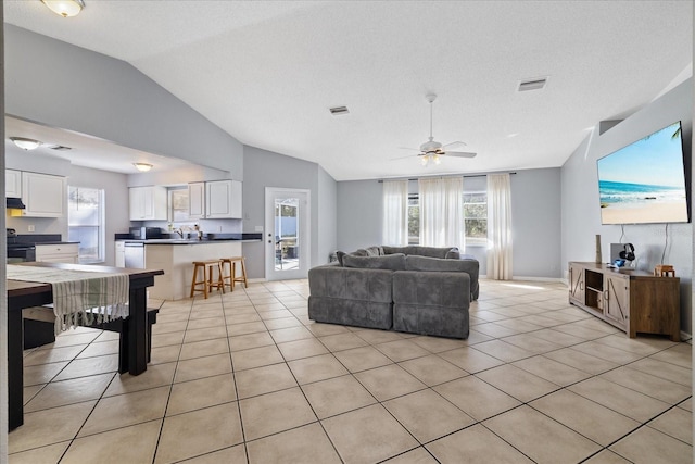 tiled living room with ceiling fan, lofted ceiling, and a textured ceiling