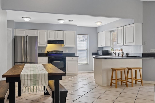 kitchen featuring black appliances, a kitchen breakfast bar, white cabinets, light tile patterned floors, and kitchen peninsula