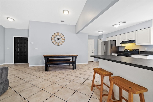 kitchen featuring black electric range, light tile patterned floors, white cabinets, and stainless steel refrigerator