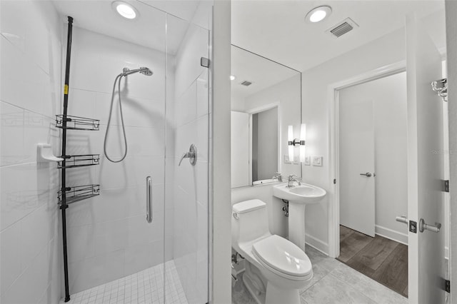 bathroom featuring toilet, an enclosed shower, and sink