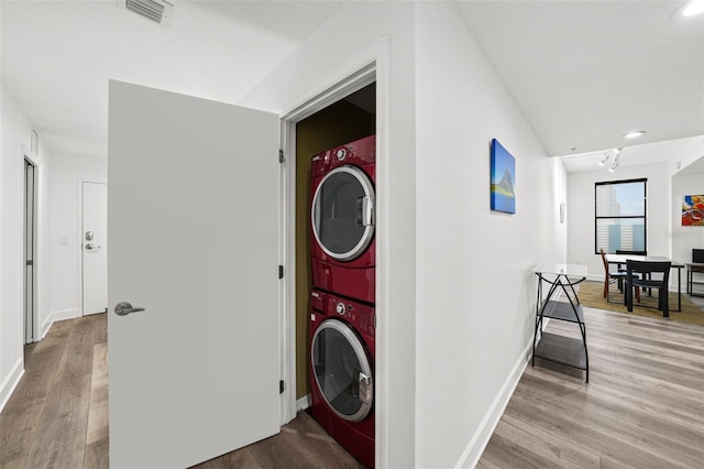 laundry room with stacked washer / dryer and light hardwood / wood-style flooring