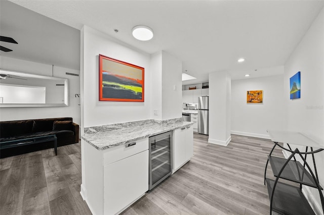 kitchen with white cabinetry, stainless steel fridge, ceiling fan, wine cooler, and light stone countertops