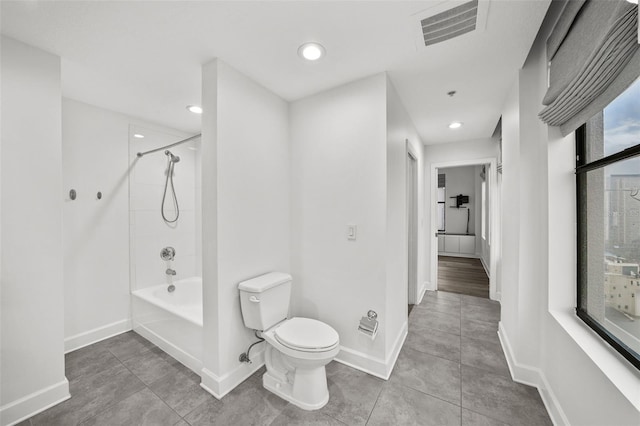 bathroom featuring toilet, tiled shower / bath, tile patterned flooring, and plenty of natural light