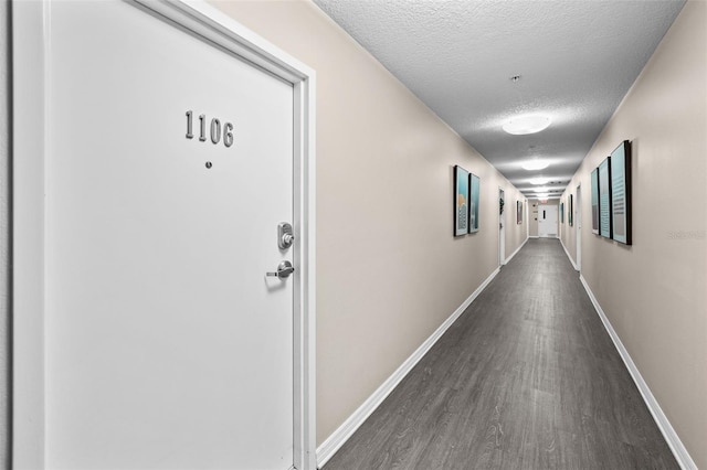 hallway with a textured ceiling and dark hardwood / wood-style floors