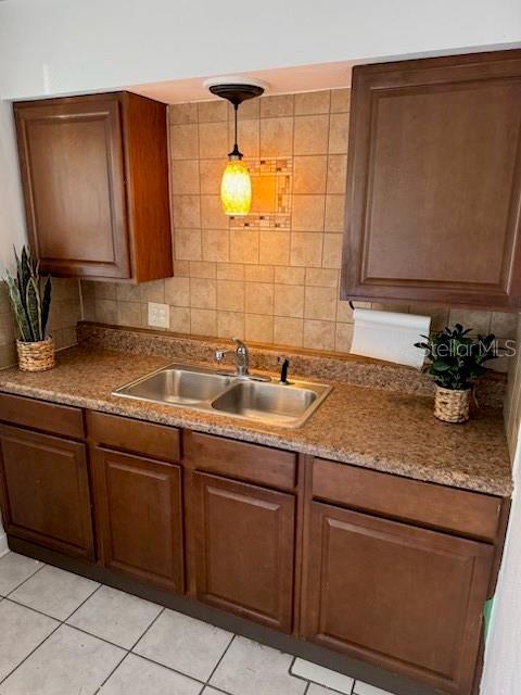 kitchen with decorative backsplash, sink, light tile patterned floors, and pendant lighting