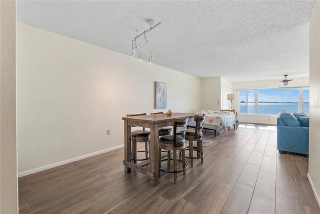 dining room featuring ceiling fan, a water view, and a textured ceiling