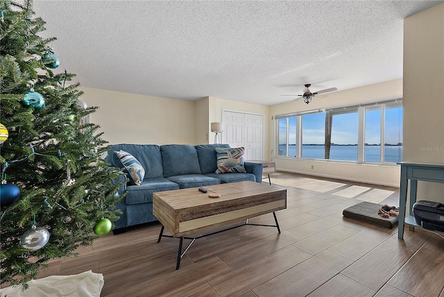 living room with a textured ceiling, ceiling fan, and a water view