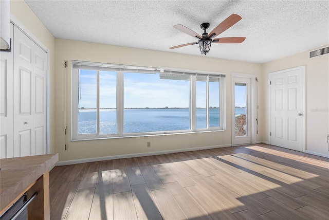 interior space featuring ceiling fan, a water view, and a textured ceiling