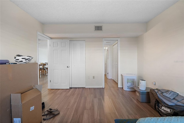 bedroom with a closet, light wood-type flooring, and a textured ceiling