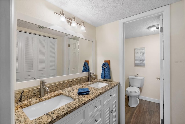 bathroom featuring toilet, hardwood / wood-style flooring, a textured ceiling, and vanity