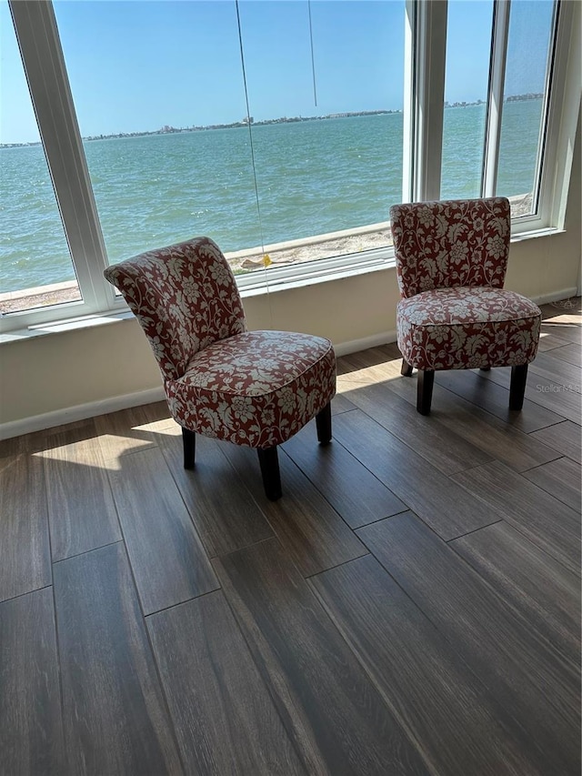 sitting room featuring baseboards, a water view, and wood finished floors