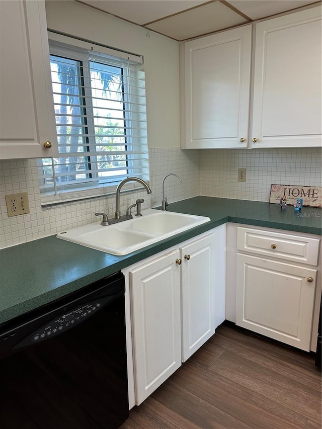 kitchen featuring dark countertops, white cabinets, black dishwasher, and a sink